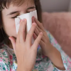Dziewczynka z katarem wyciera nos chusteczką. Może potrzebuje antybiotyku na zatoki.
