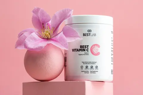 Różowa kula z kwiatem i opakowanie suplementu Best Vitamin C, zawierającego kwas askorbinowy.