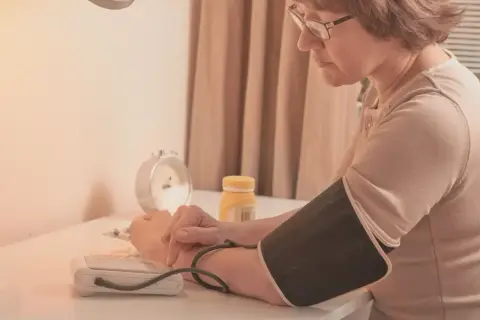 Kobieta mierzy ciśnienie, obok leży lek telmisartan.