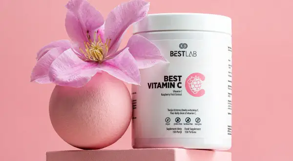 Różowa kula z kwiatem i opakowanie suplementu Best Vitamin C, zawierającego kwas askorbinowy.