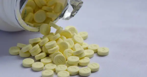 Żółte tabletki, niektóre z literą "D", inne z cyfrą "5", wysypują się z białego pojemnika. To może być valium.